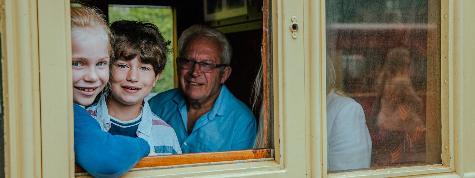 A family on board the Isle of Man Steam Railway, the kids looking out of the window towards the camera